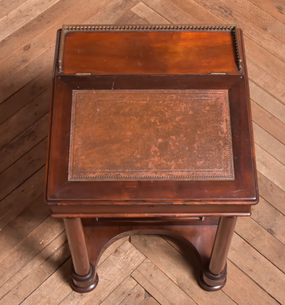 A Victorian rosewood Davenport desk featuring a slanted leather-inset writing surface, brass gallery rail, turned front columns, and side drawers. View XIV