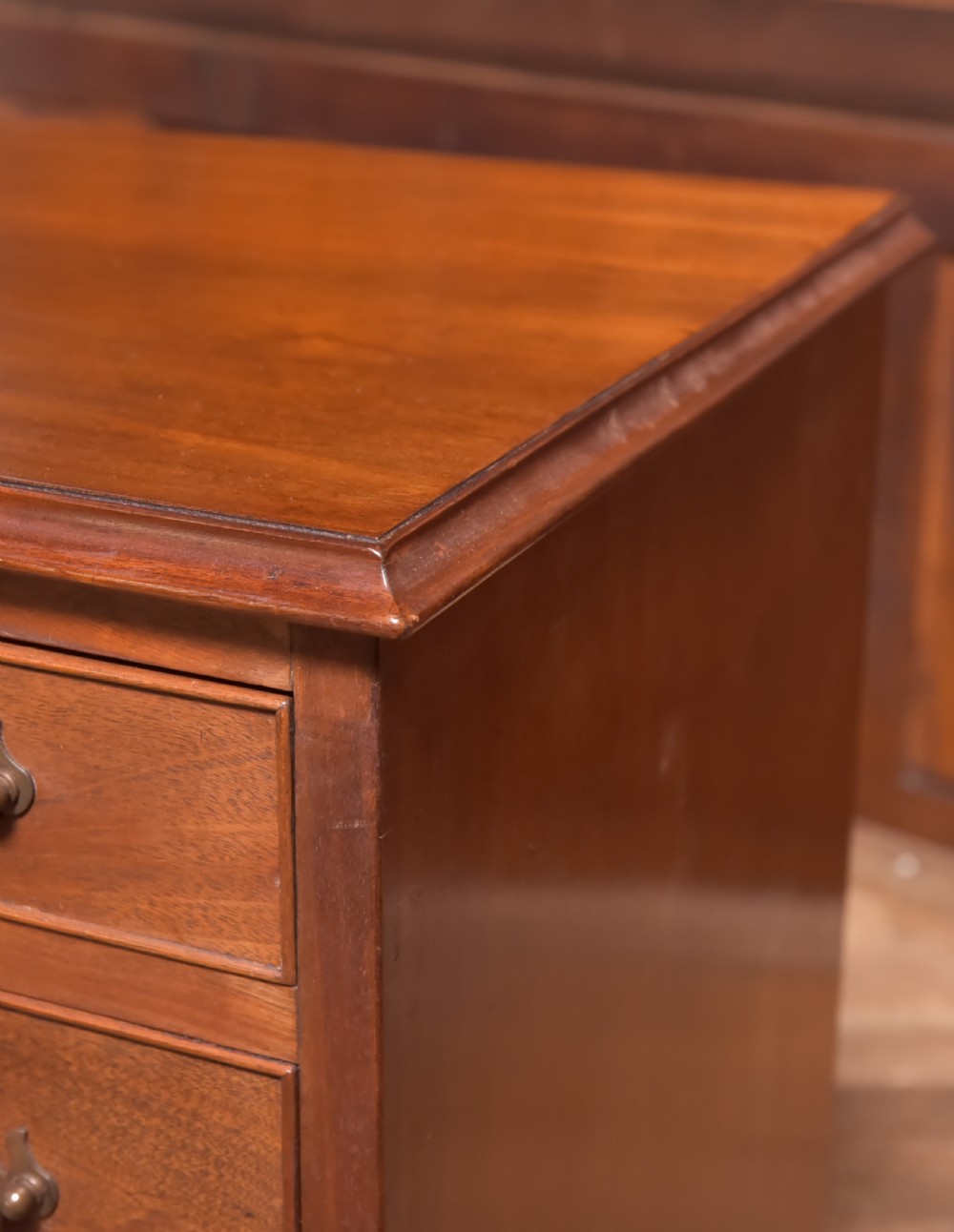 An antique Georgian mahogany kneehole desk featuring seven drawers with brass batwing handles, a recessed central cupboard, and shaped bracket feet. View VII