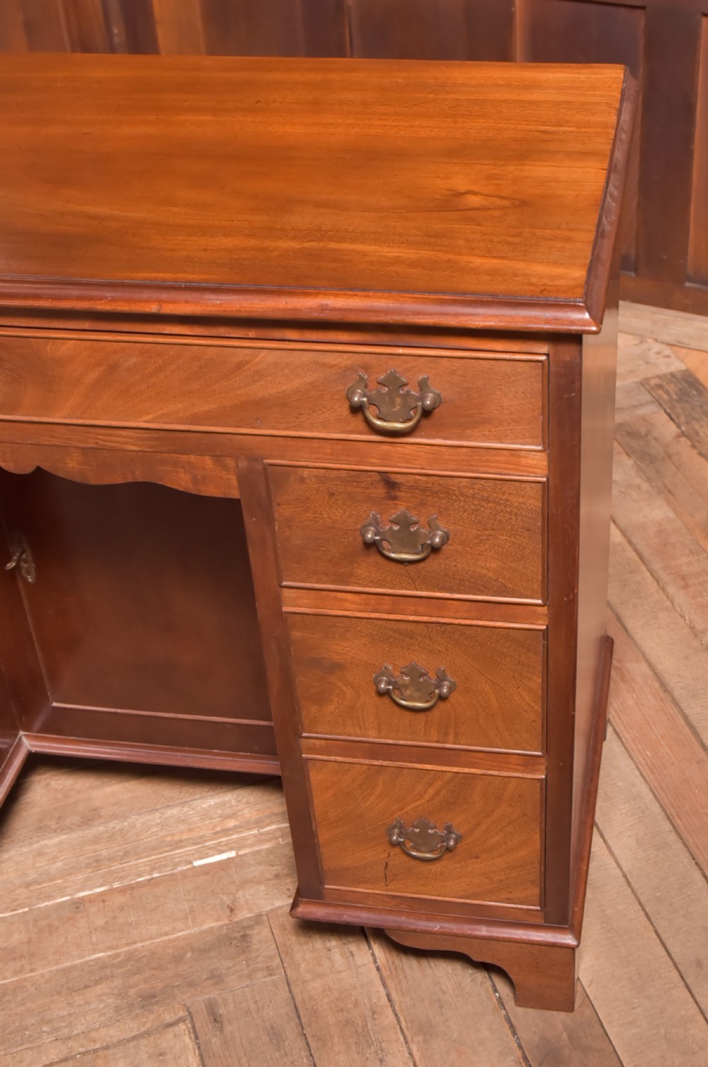 An antique Georgian mahogany kneehole desk featuring seven drawers with brass batwing handles, a recessed central cupboard, and shaped bracket feet. View VIII