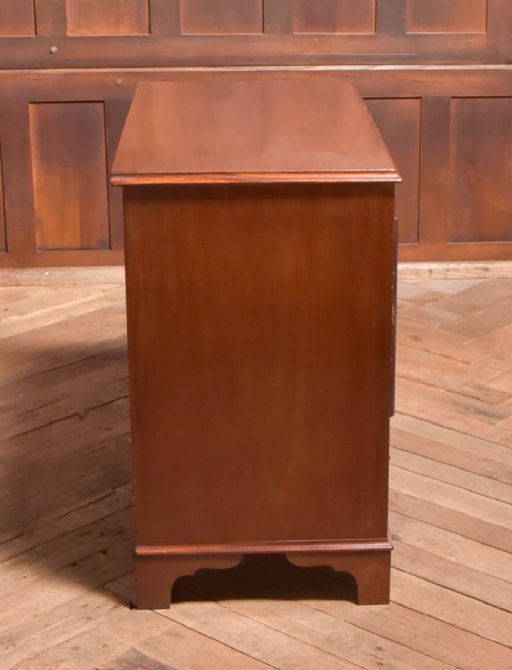 An antique Georgian mahogany kneehole desk featuring seven drawers with brass batwing handles, a recessed central cupboard, and shaped bracket feet. View XV