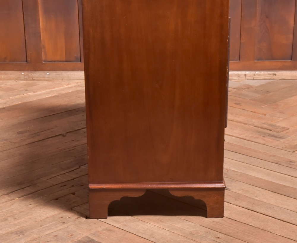 An antique Georgian mahogany kneehole desk featuring seven drawers with brass batwing handles, a recessed central cupboard, and shaped bracket feet. View XVI
