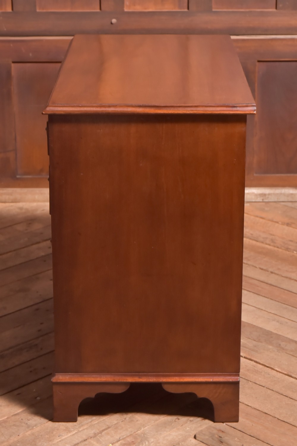 An antique Georgian mahogany kneehole desk featuring seven drawers with brass batwing handles, a recessed central cupboard, and shaped bracket feet. View XVIII