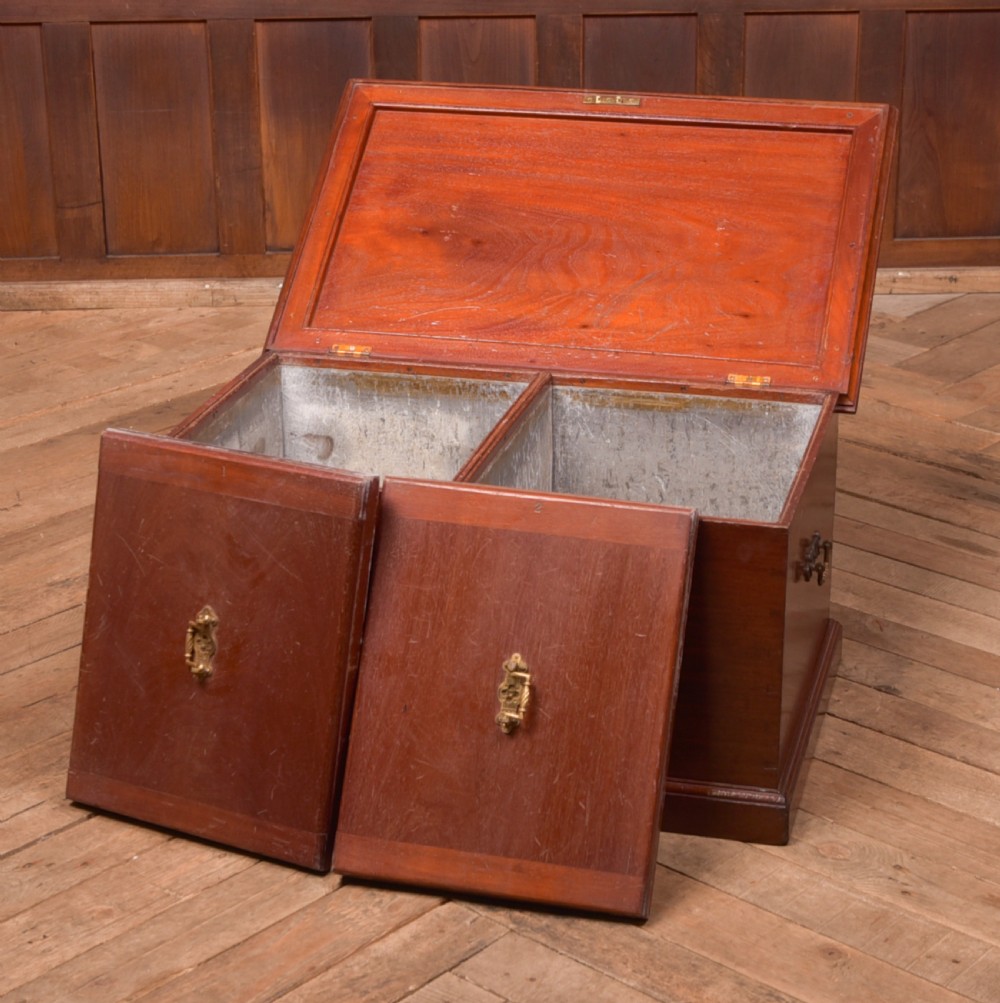 An antique reddish brown mahogany rectangular blanket box featuring a hinged lid, brass side carrying handles, a keyhole, and a moulded plinth base. View IV