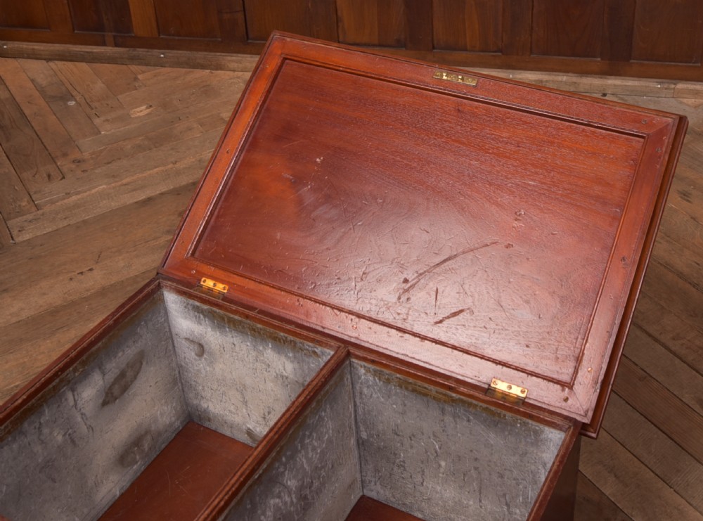 An antique reddish brown mahogany rectangular blanket box featuring a hinged lid, brass side carrying handles, a keyhole, and a moulded plinth base. View V
