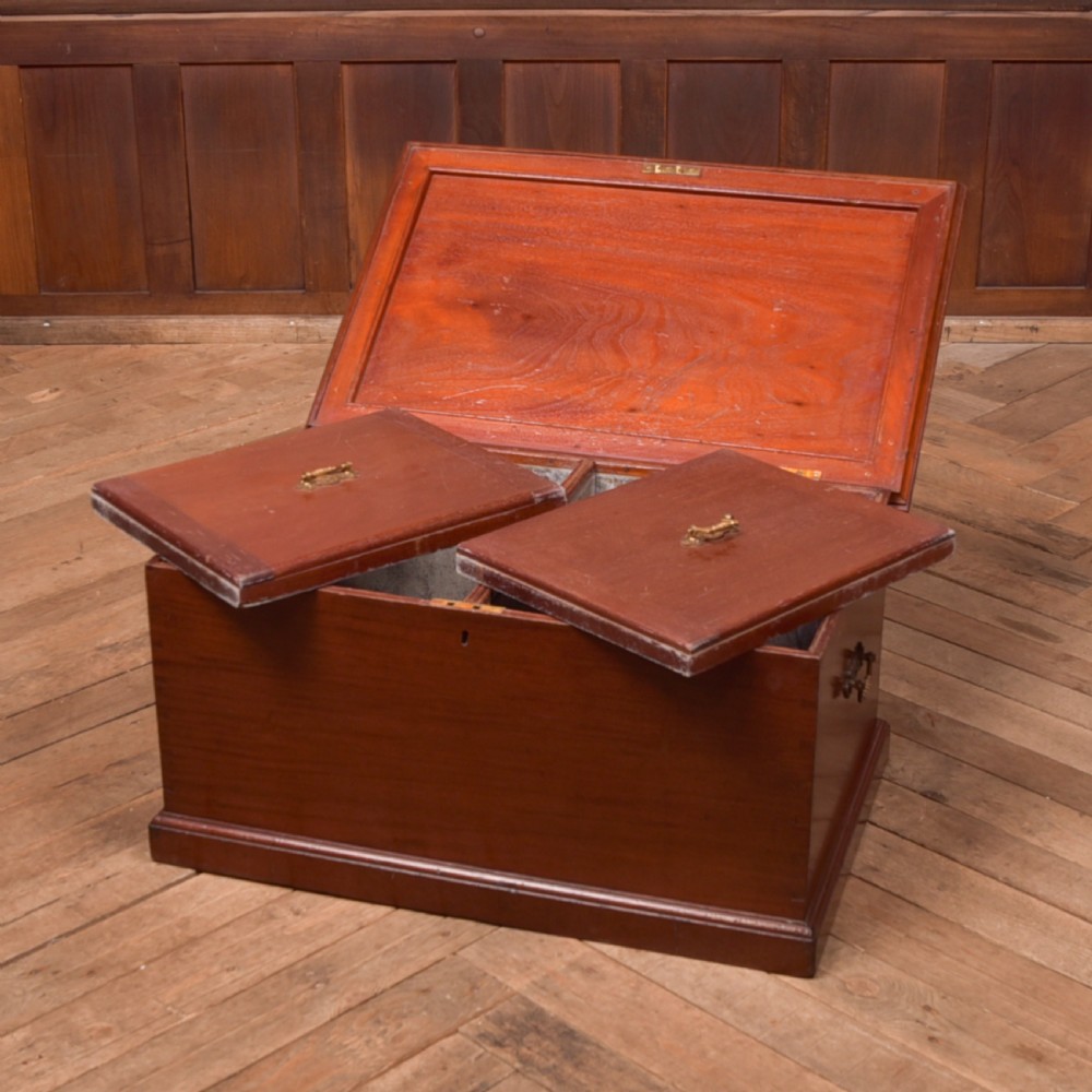 An antique reddish brown mahogany rectangular blanket box featuring a hinged lid, brass side carrying handles, a keyhole, and a moulded plinth base. View VI
