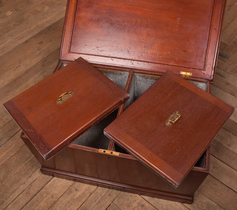 An antique reddish brown mahogany rectangular blanket box featuring a hinged lid, brass side carrying handles, a keyhole, and a moulded plinth base. View VII