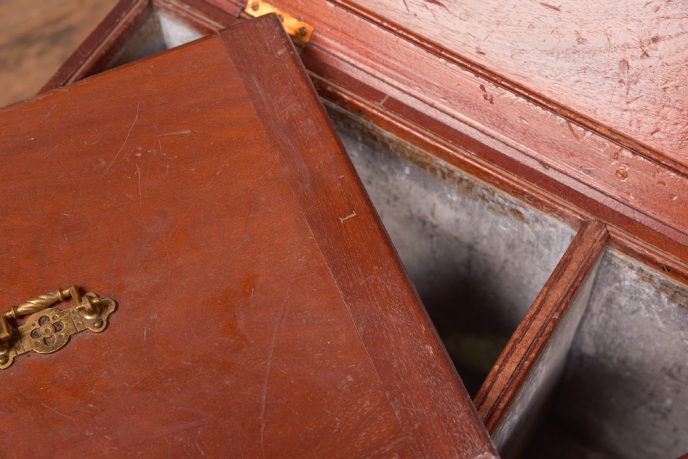 An antique reddish brown mahogany rectangular blanket box featuring a hinged lid, brass side carrying handles, a keyhole, and a moulded plinth base. View IX