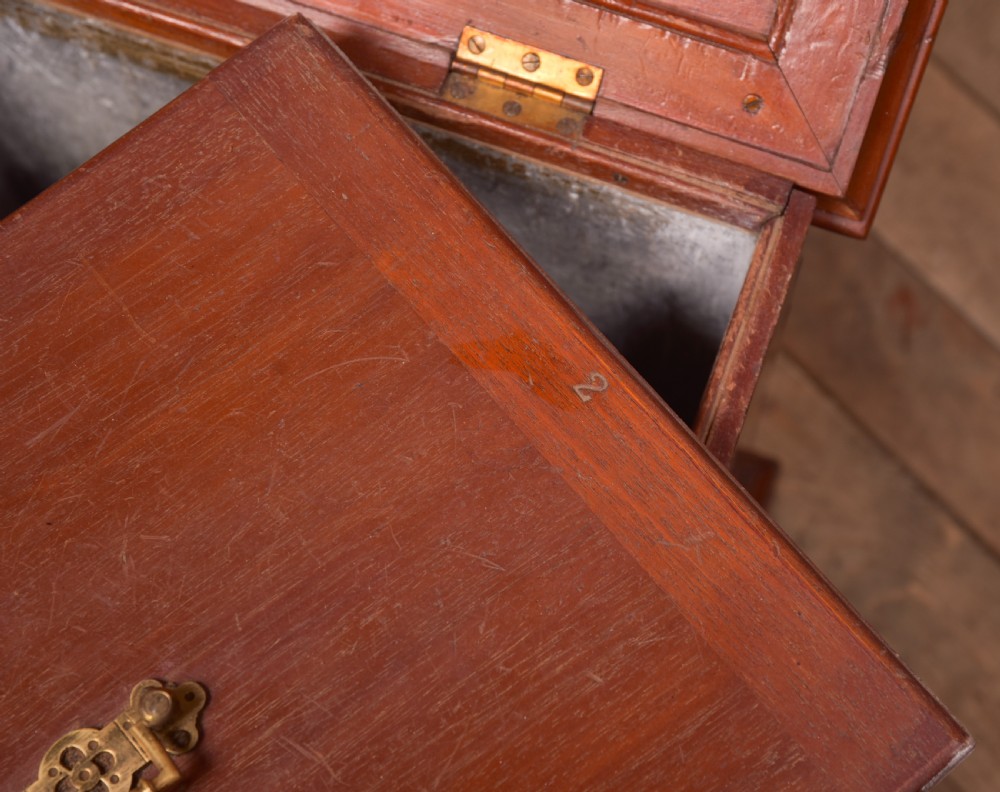 An antique reddish brown mahogany rectangular blanket box featuring a hinged lid, brass side carrying handles, a keyhole, and a moulded plinth base. View X