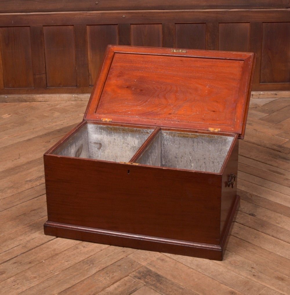 An antique reddish brown mahogany rectangular blanket box featuring a hinged lid, brass side carrying handles, a keyhole, and a moulded plinth base. View XII