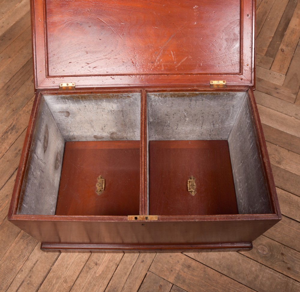 An antique reddish brown mahogany rectangular blanket box featuring a hinged lid, brass side carrying handles, a keyhole, and a moulded plinth base. View XIII