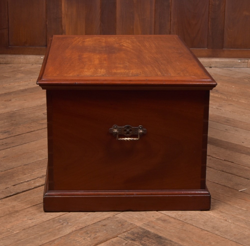 An antique reddish brown mahogany rectangular blanket box featuring a hinged lid, brass side carrying handles, a keyhole, and a moulded plinth base. View XVII