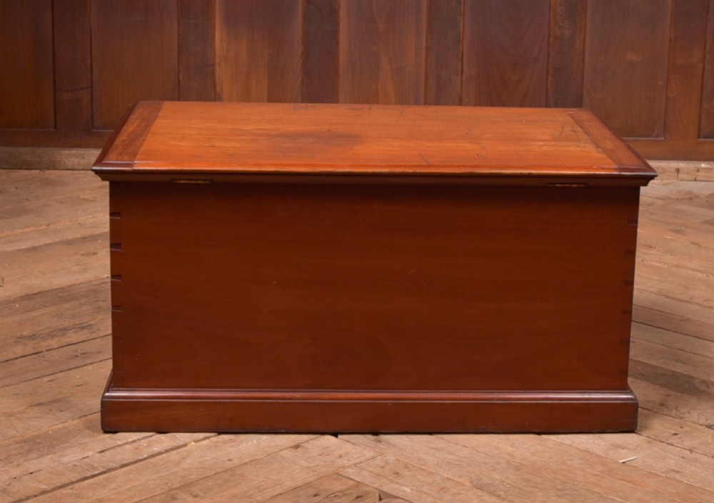 An antique reddish brown mahogany rectangular blanket box featuring a hinged lid, brass side carrying handles, a keyhole, and a moulded plinth base. View XVIII