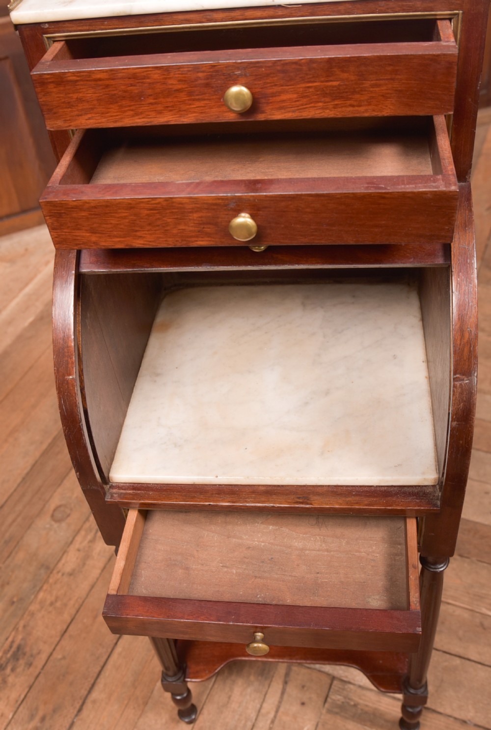 A French mahogany roll-top pot cupboard with a marble top, brass gallery, drawers, slatted tambour front, and turned legs. View V