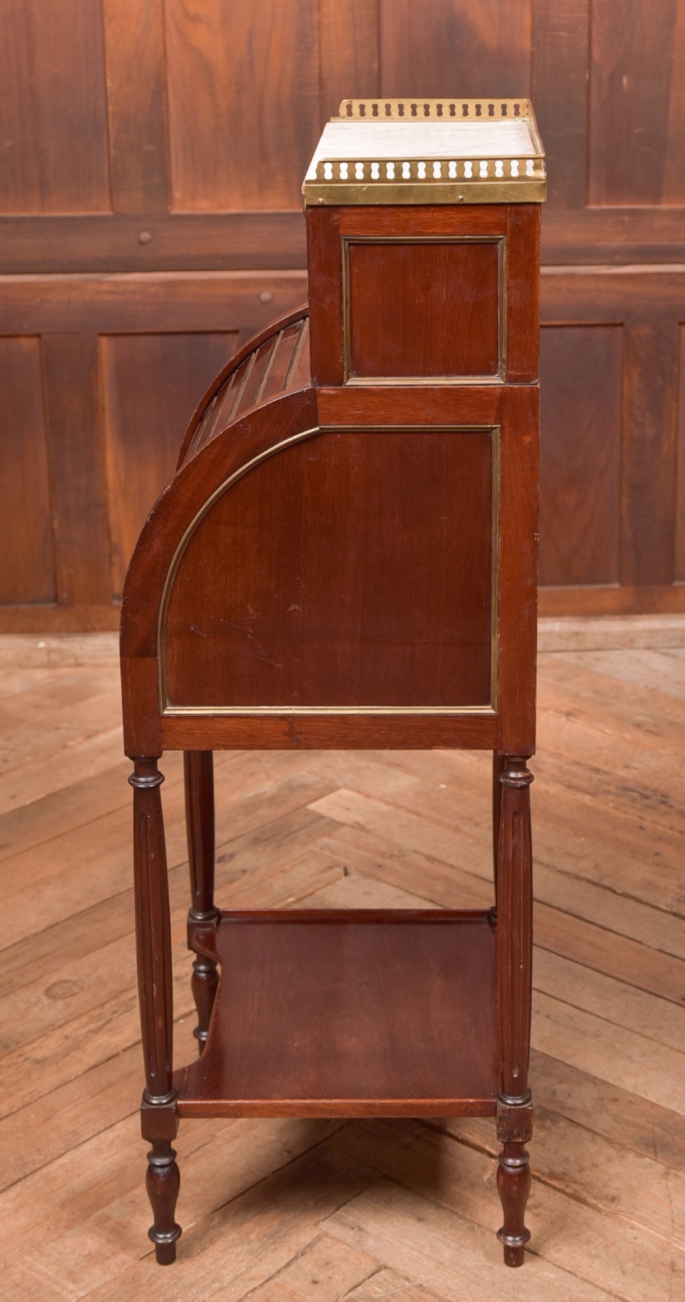 A French mahogany roll-top pot cupboard with a marble top, brass gallery, drawers, slatted tambour front, and turned legs. View VII