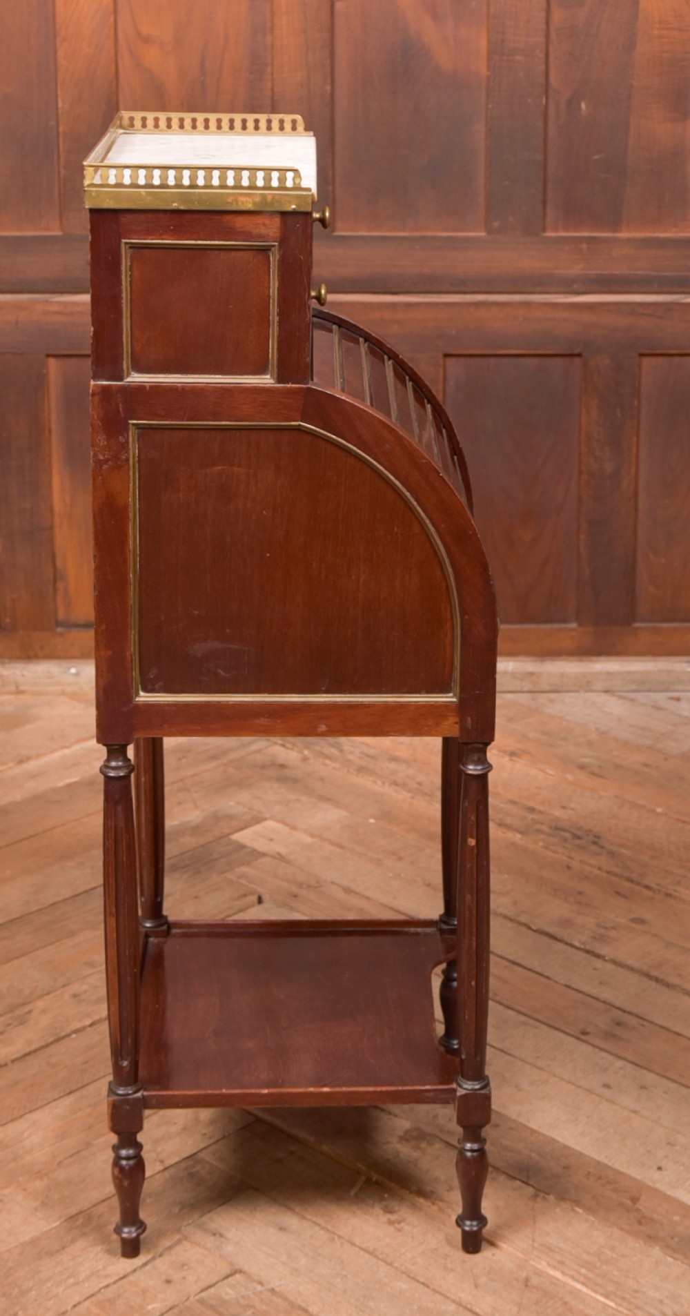 A French mahogany roll-top pot cupboard with a marble top, brass gallery, drawers, slatted tambour front, and turned legs. View IX