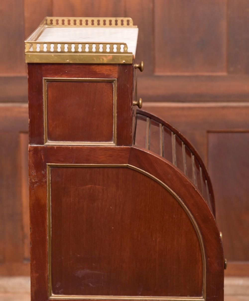 A French mahogany roll-top pot cupboard with a marble top, brass gallery, drawers, slatted tambour front, and turned legs. View XIV