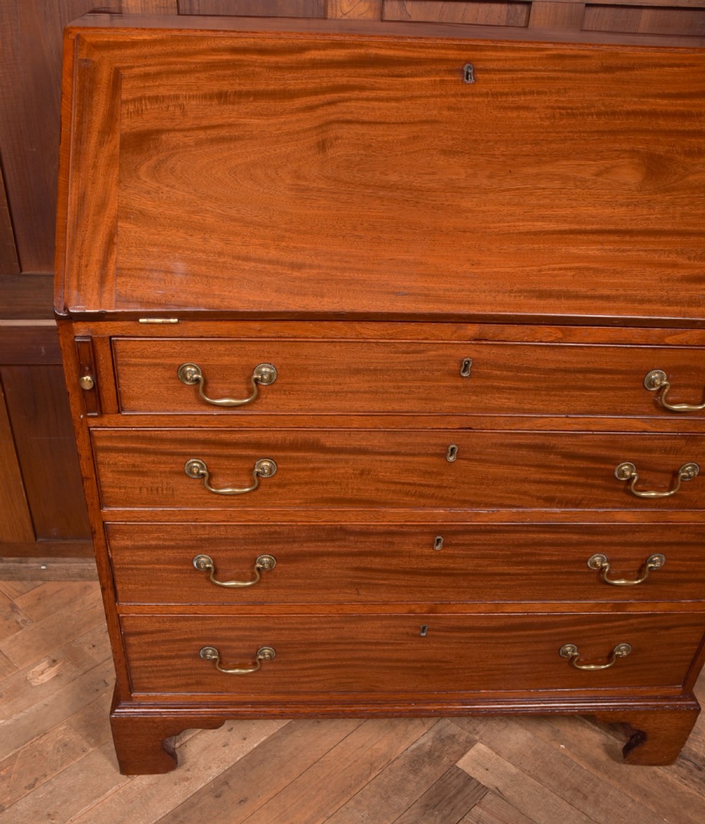 A Georgian mahogany writing bureau featuring a sloped fall-front writing flap above four graduated drawers with brass swan-neck handles and bracket feet. View II
