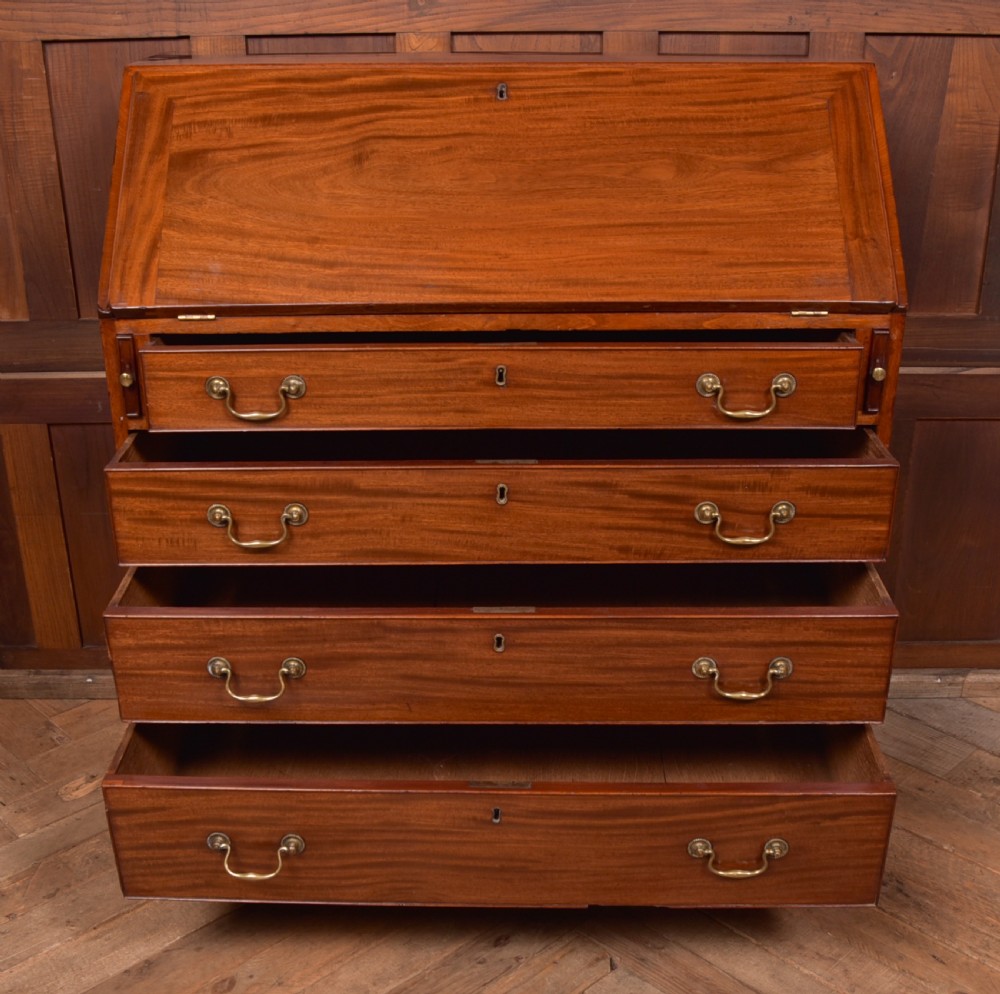 A Georgian mahogany writing bureau featuring a sloped fall-front writing flap above four graduated drawers with brass swan-neck handles and bracket feet. View V