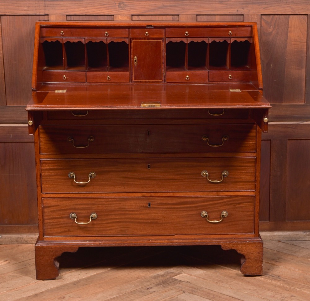 A Georgian mahogany writing bureau featuring a sloped fall-front writing flap above four graduated drawers with brass swan-neck handles and bracket feet. View IX