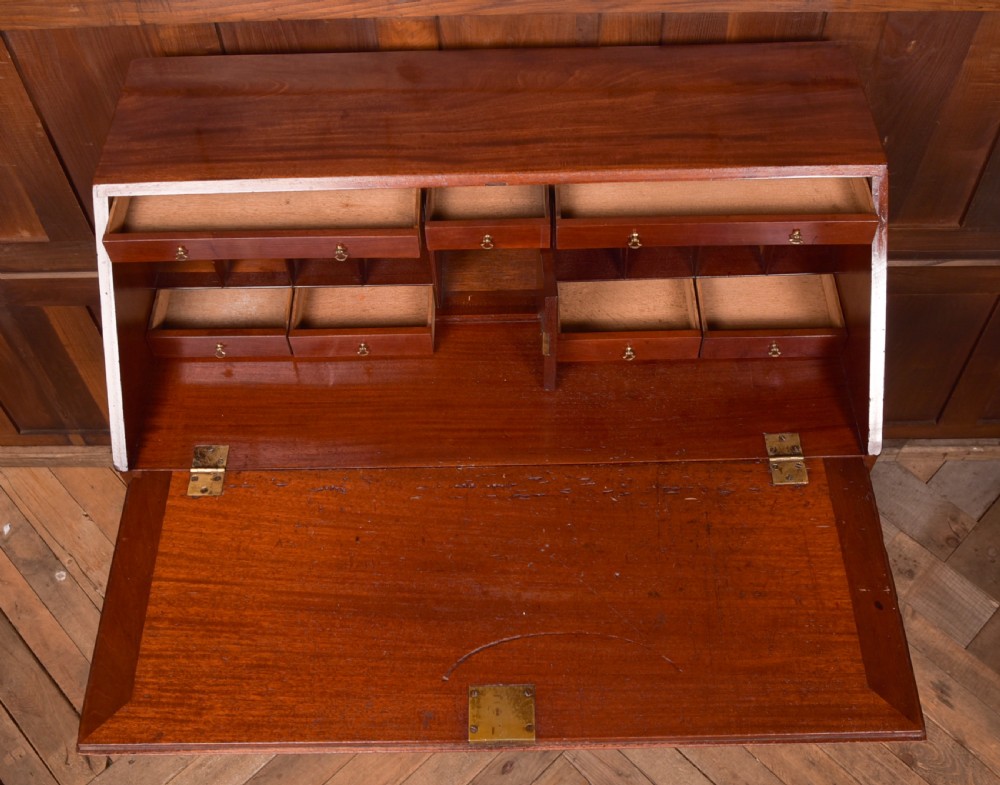 A Georgian mahogany writing bureau featuring a sloped fall-front writing flap above four graduated drawers with brass swan-neck handles and bracket feet. View XI