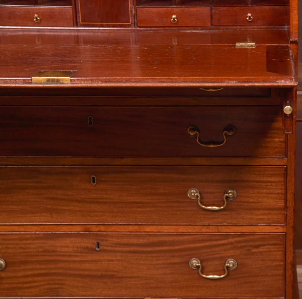 A Georgian mahogany writing bureau featuring a sloped fall-front writing flap above four graduated drawers with brass swan-neck handles and bracket feet. View XIII