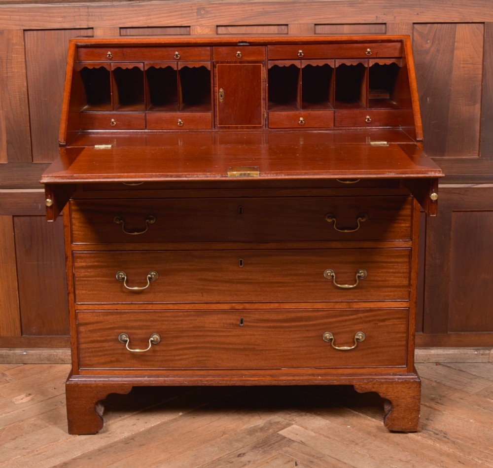 A Georgian mahogany writing bureau featuring a sloped fall-front writing flap above four graduated drawers with brass swan-neck handles and bracket feet. View XIV