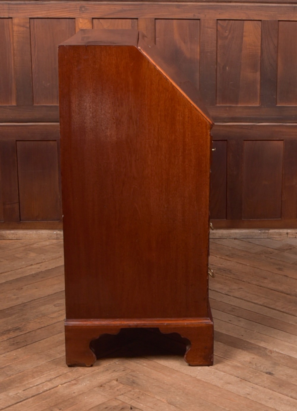 A Georgian mahogany writing bureau featuring a sloped fall-front writing flap above four graduated drawers with brass swan-neck handles and bracket feet. View XVII