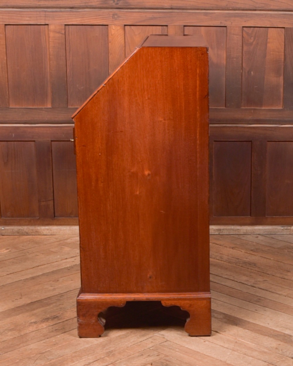A Georgian mahogany writing bureau featuring a sloped fall-front writing flap above four graduated drawers with brass swan-neck handles and bracket feet. View XVIII