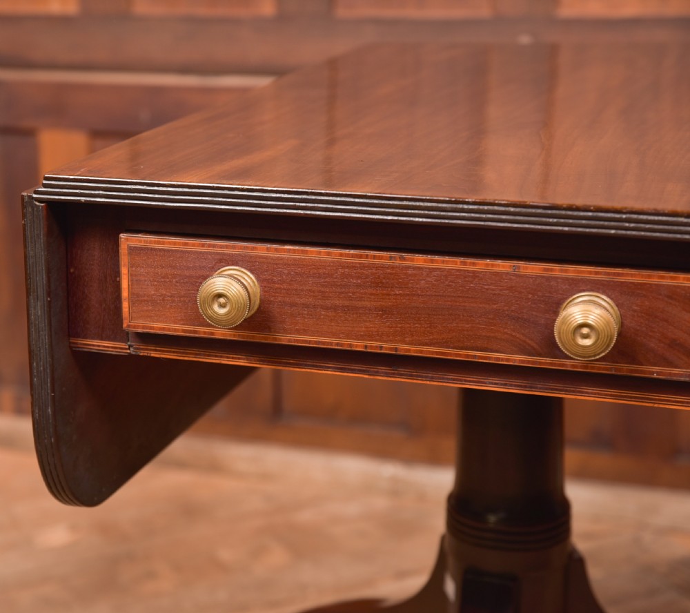 A dark mahogany Regency Pembroke table featuring a drop-leaf top, a single drawer with brass knobs, and a central turned pedestal resting on four splayed legs with brass castors. View II
