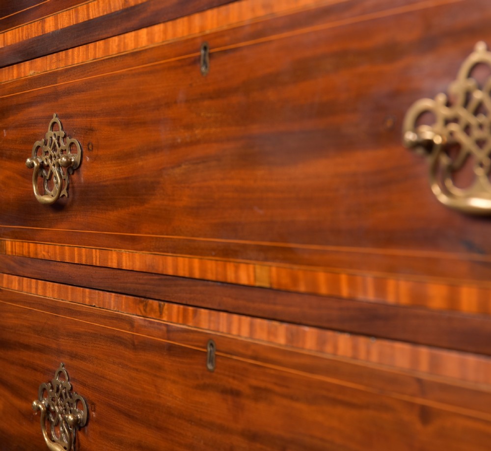 A tall Georgian mahogany chest on chest featuring inlaid drawer borders, brass handles, dentil cornice detail, and bracket feet. View III