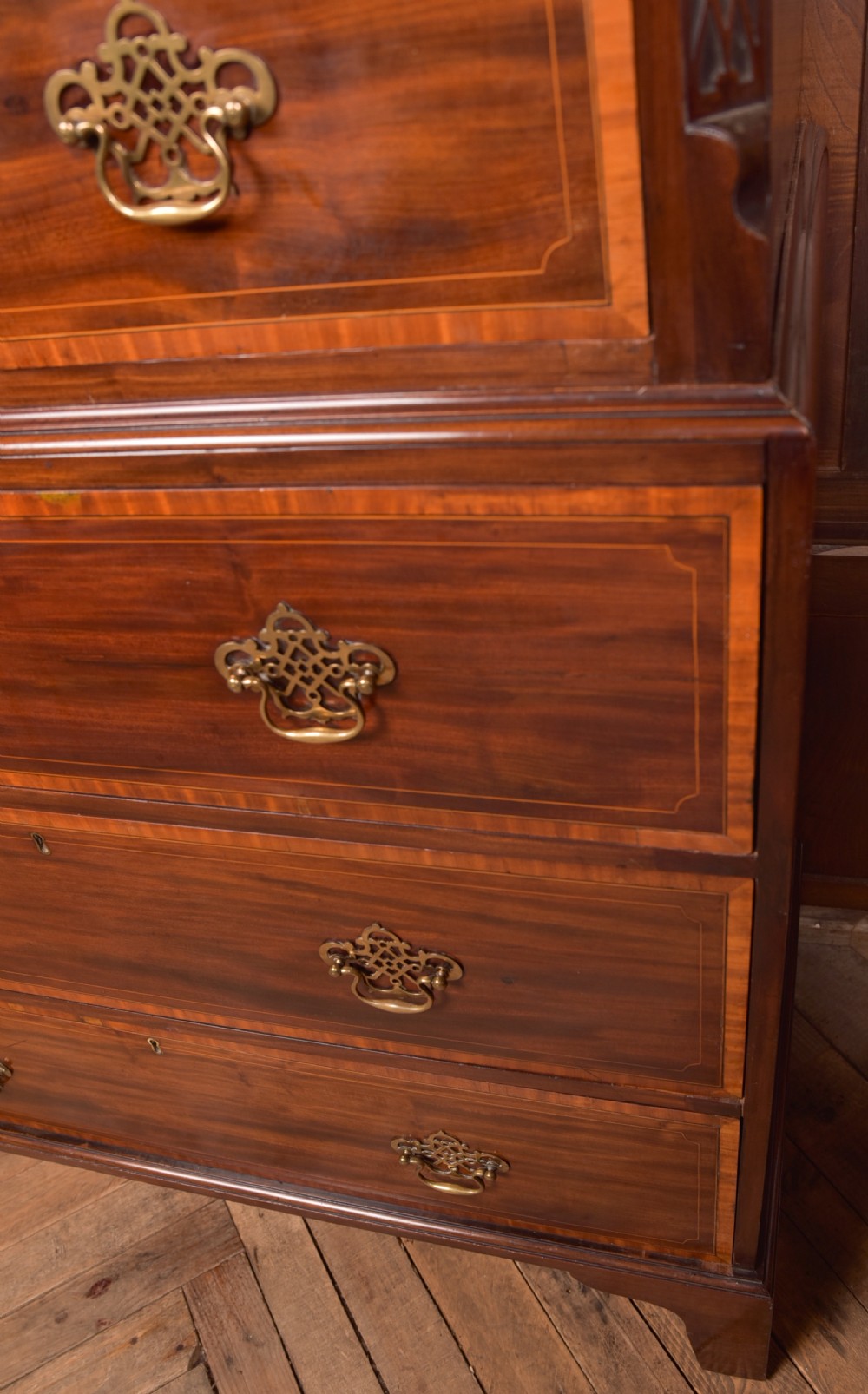 A tall Georgian mahogany chest on chest featuring inlaid drawer borders, brass handles, dentil cornice detail, and bracket feet. View V
