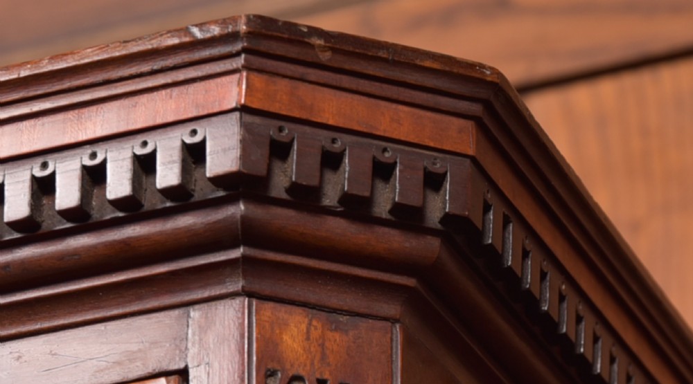 A tall Georgian mahogany chest on chest featuring inlaid drawer borders, brass handles, dentil cornice detail, and bracket feet. View VI