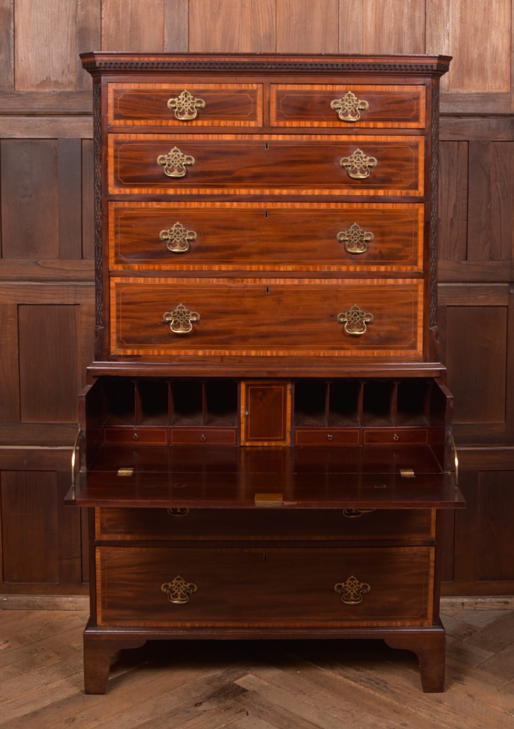 A tall Georgian mahogany chest on chest featuring inlaid drawer borders, brass handles, dentil cornice detail, and bracket feet. View IX