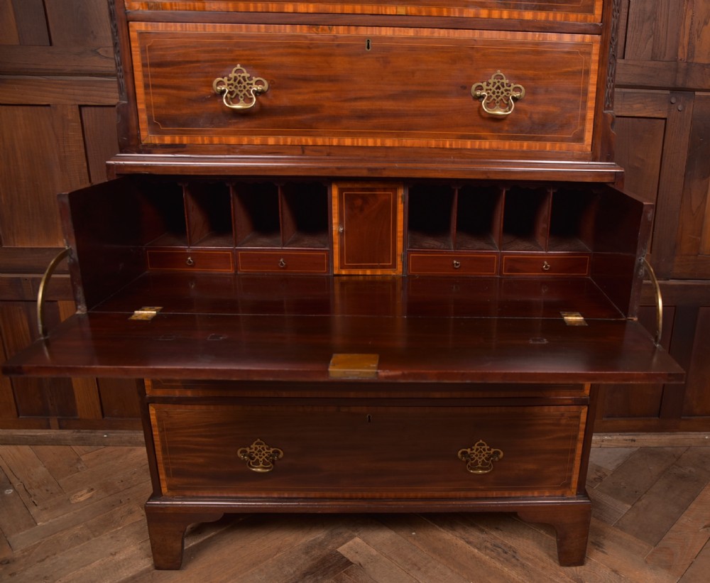 A tall Georgian mahogany chest on chest featuring inlaid drawer borders, brass handles, dentil cornice detail, and bracket feet. View X