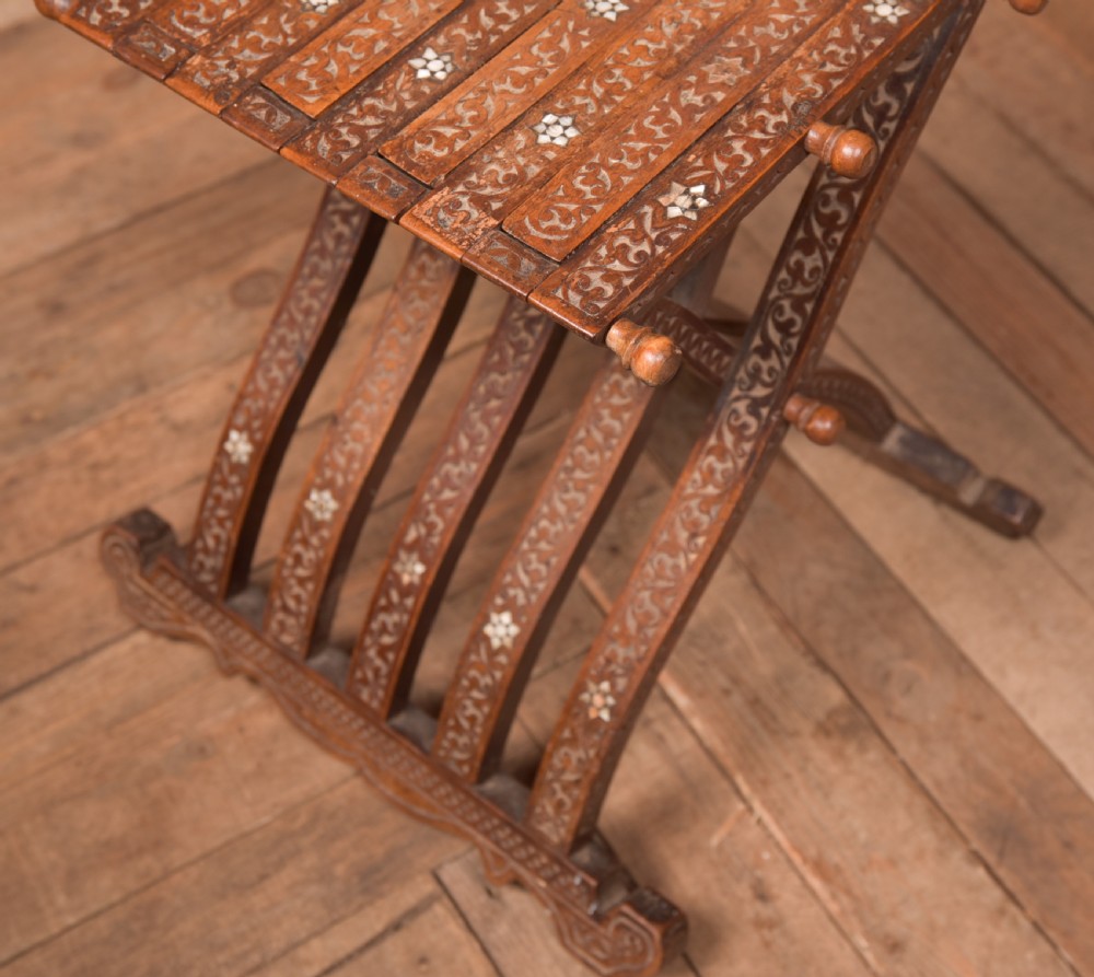 An intricate carved brown wooden Islamic folding chair decorated with mother-of-pearl inlay and calligraphic details. View IV