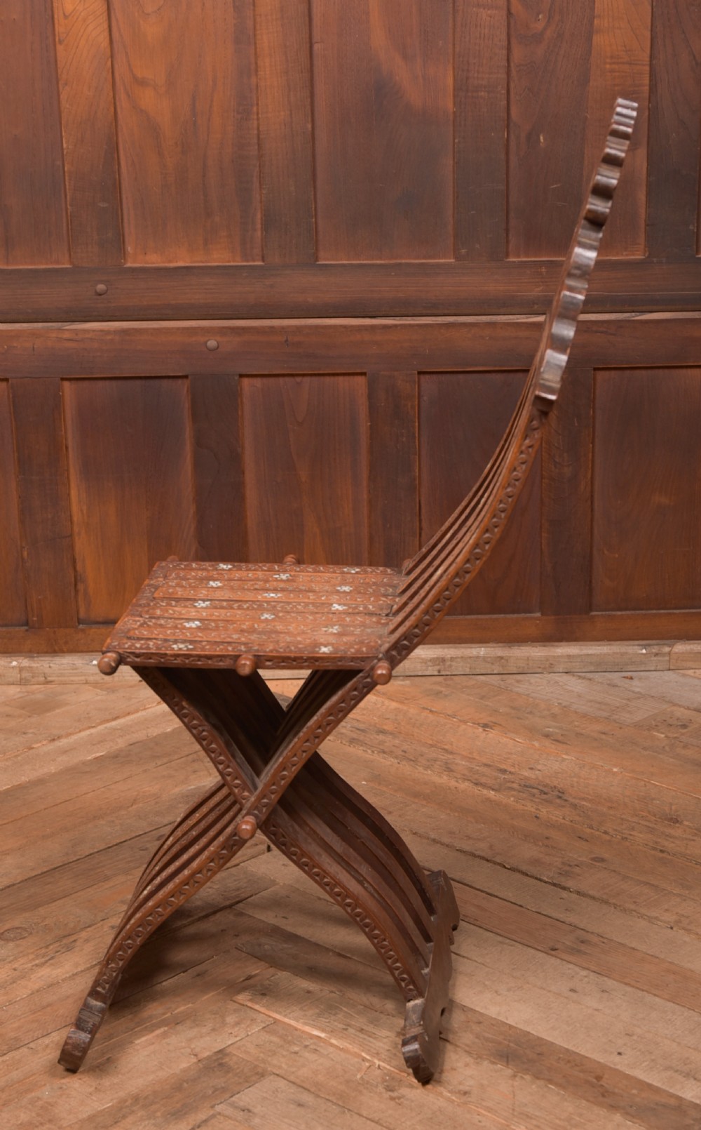An intricate carved brown wooden Islamic folding chair decorated with mother-of-pearl inlay and calligraphic details. View VII