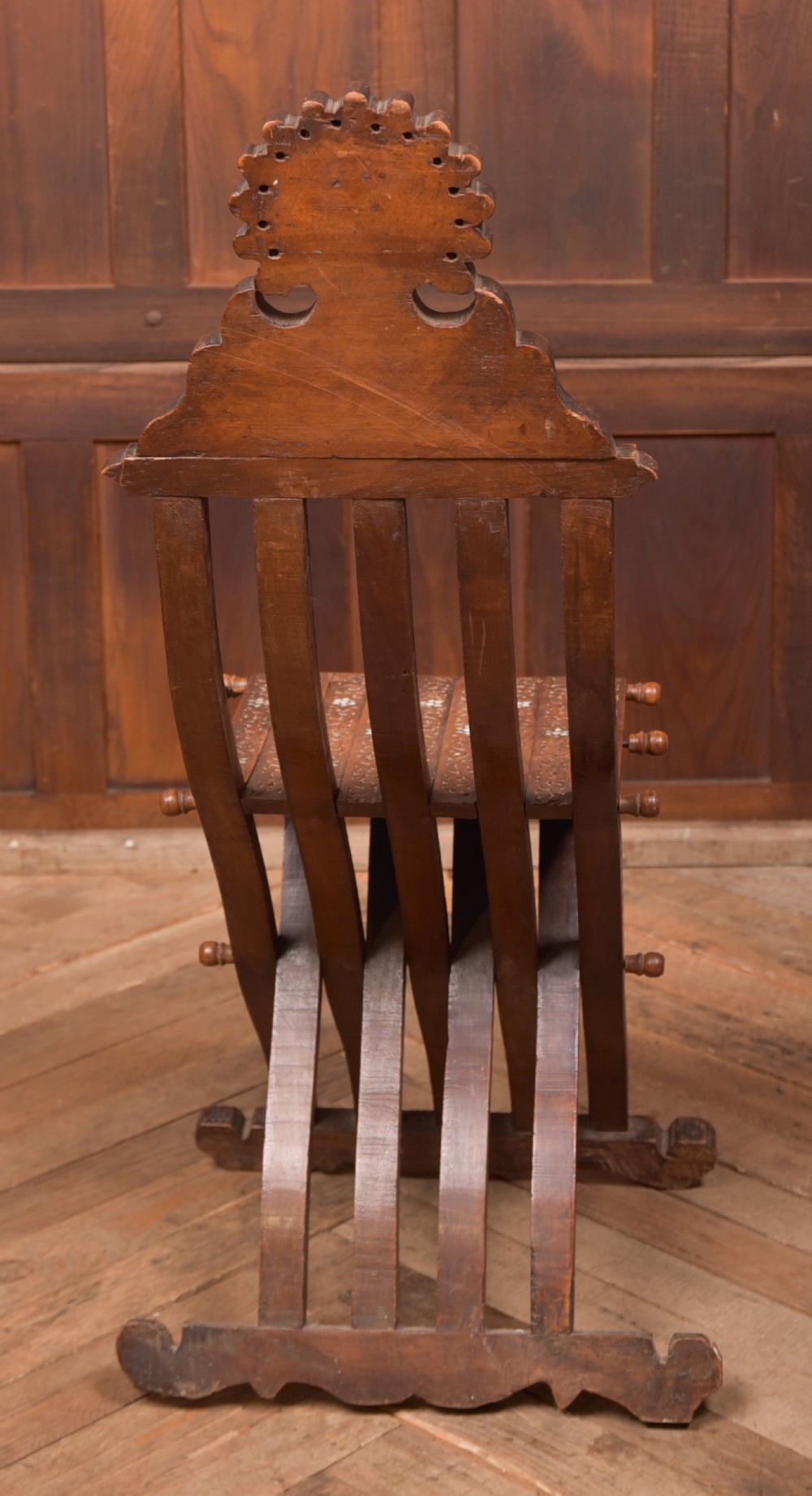 An intricate carved brown wooden Islamic folding chair decorated with mother-of-pearl inlay and calligraphic details. View VIII