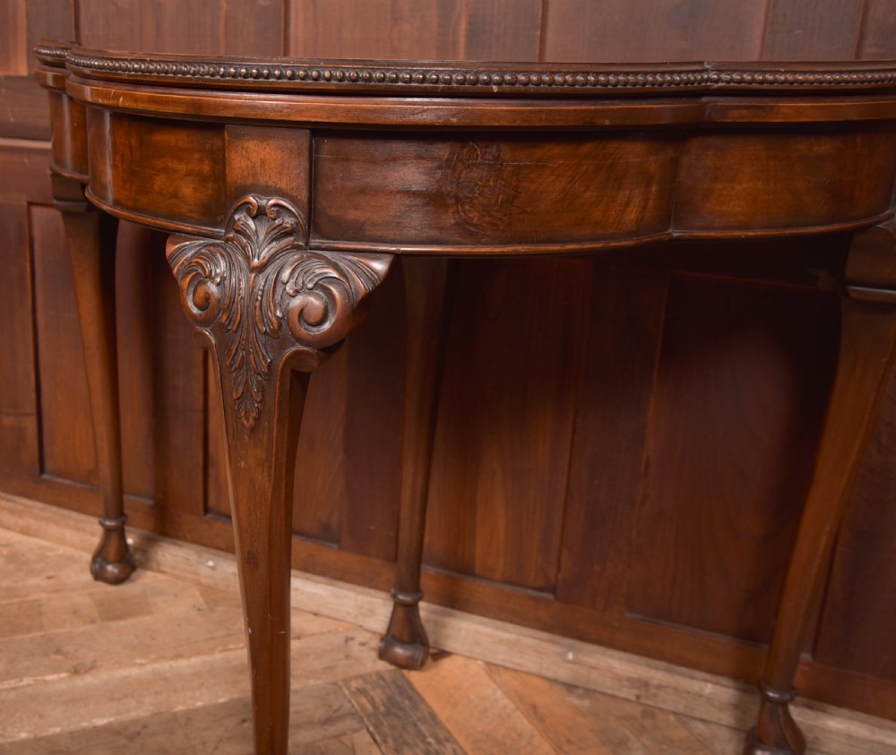 An Edwardian mahogany demi-lune card table featuring carved cabriole legs and a polished fold-over top. View II