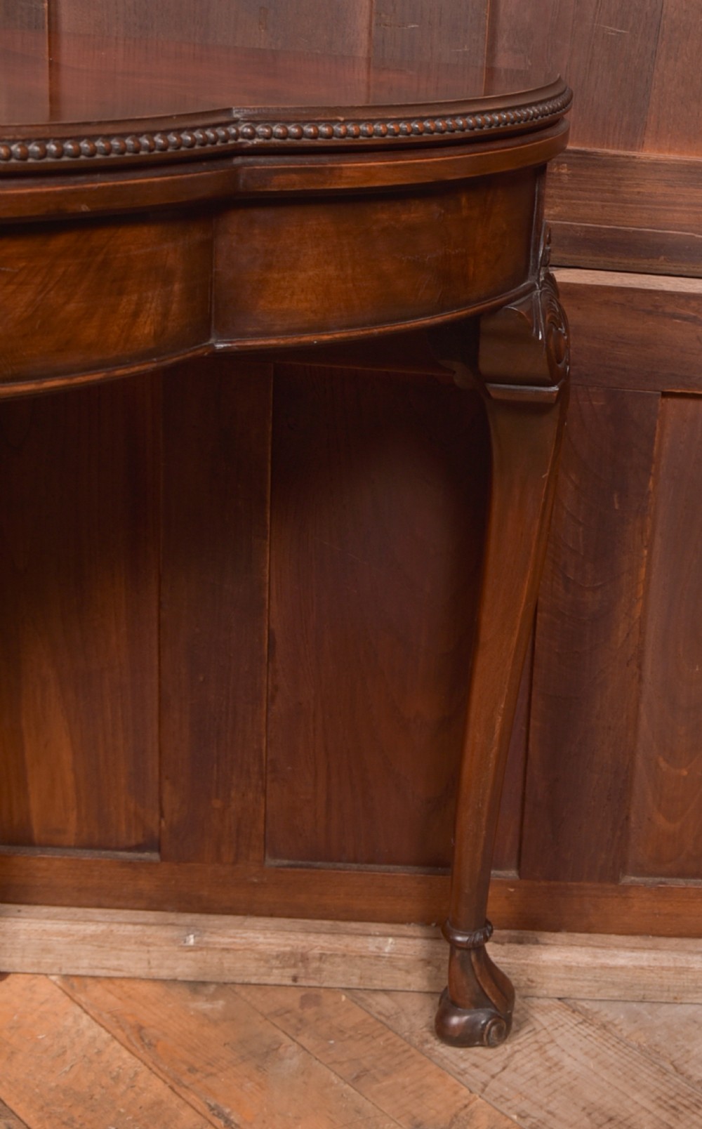An Edwardian mahogany demi-lune card table featuring carved cabriole legs and a polished fold-over top. View III