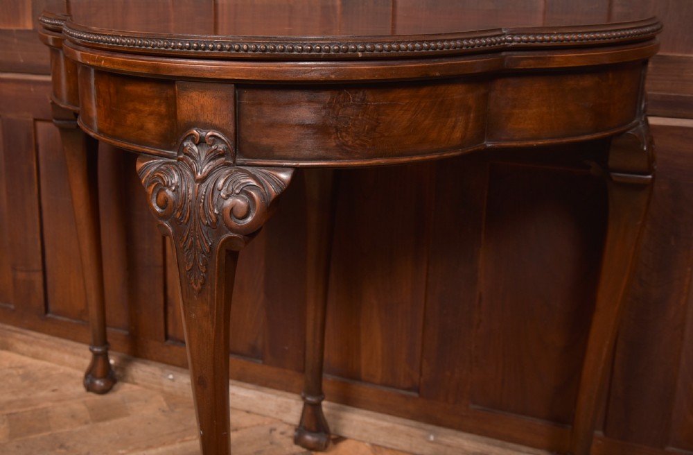 An Edwardian mahogany demi-lune card table featuring carved cabriole legs and a polished fold-over top. View VI