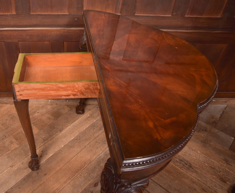 An Edwardian mahogany demi-lune card table featuring carved cabriole legs and a polished fold-over top. View IX
