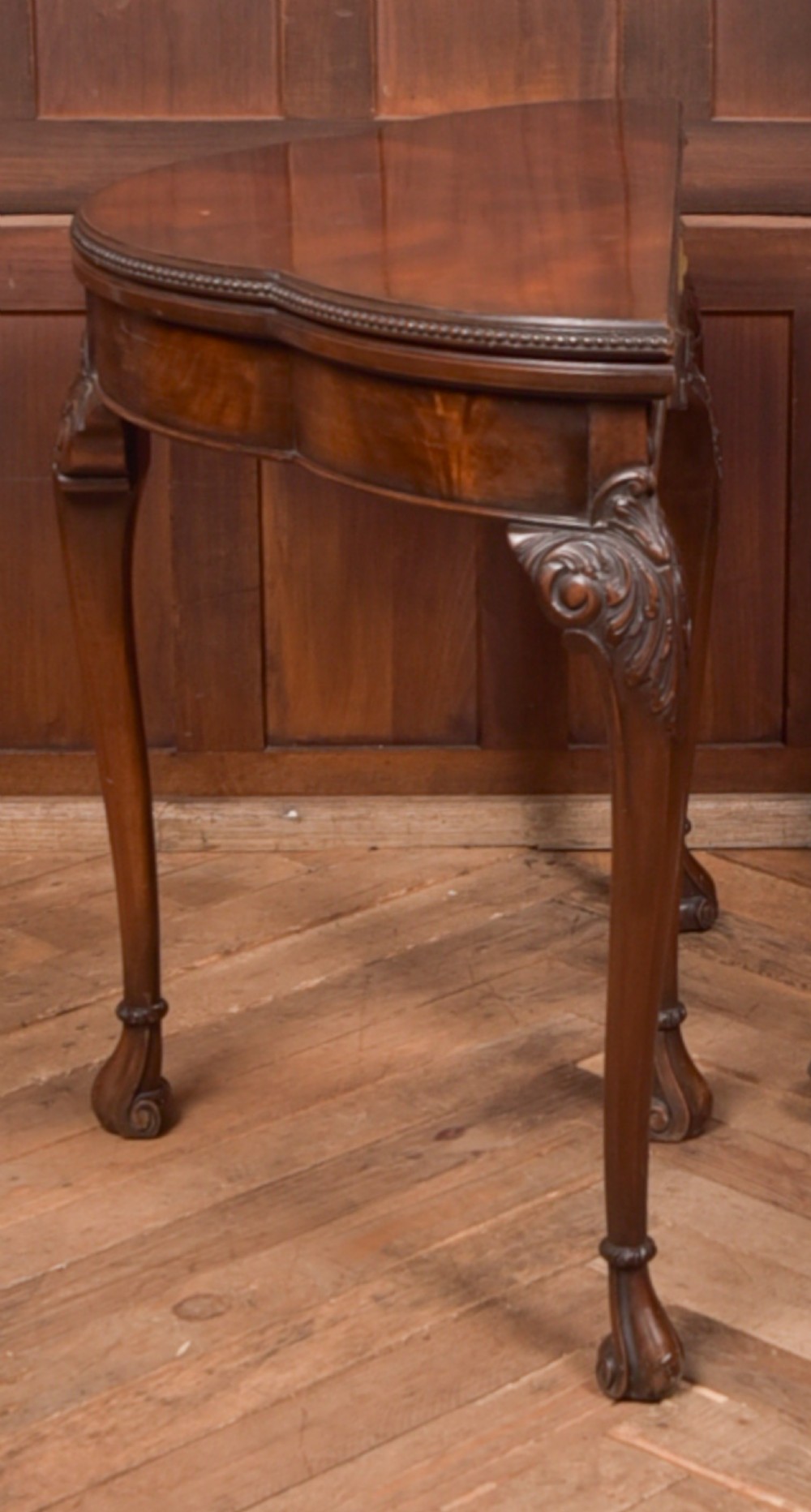 An Edwardian mahogany demi-lune card table featuring carved cabriole legs and a polished fold-over top. View XII