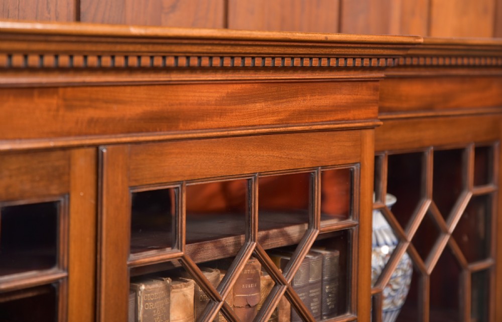 A large mahogany Chinese Chippendale style breakout bookcase featuring four glazed doors with lattice astragal glazing and dentil moulding along the top. View VI