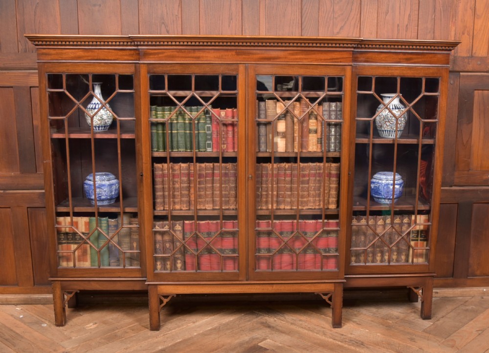 A large mahogany Chinese Chippendale style breakout bookcase featuring four glazed doors with lattice astragal glazing and dentil moulding along the top. View VII