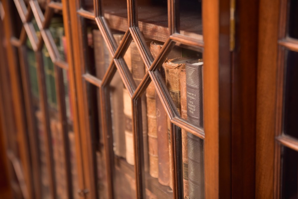 A large mahogany Chinese Chippendale style breakout bookcase featuring four glazed doors with lattice astragal glazing and dentil moulding along the top. View IX