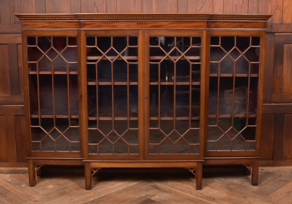 A large mahogany Chinese Chippendale style breakout bookcase featuring four glazed doors with lattice astragal glazing and dentil moulding along the top. View XI