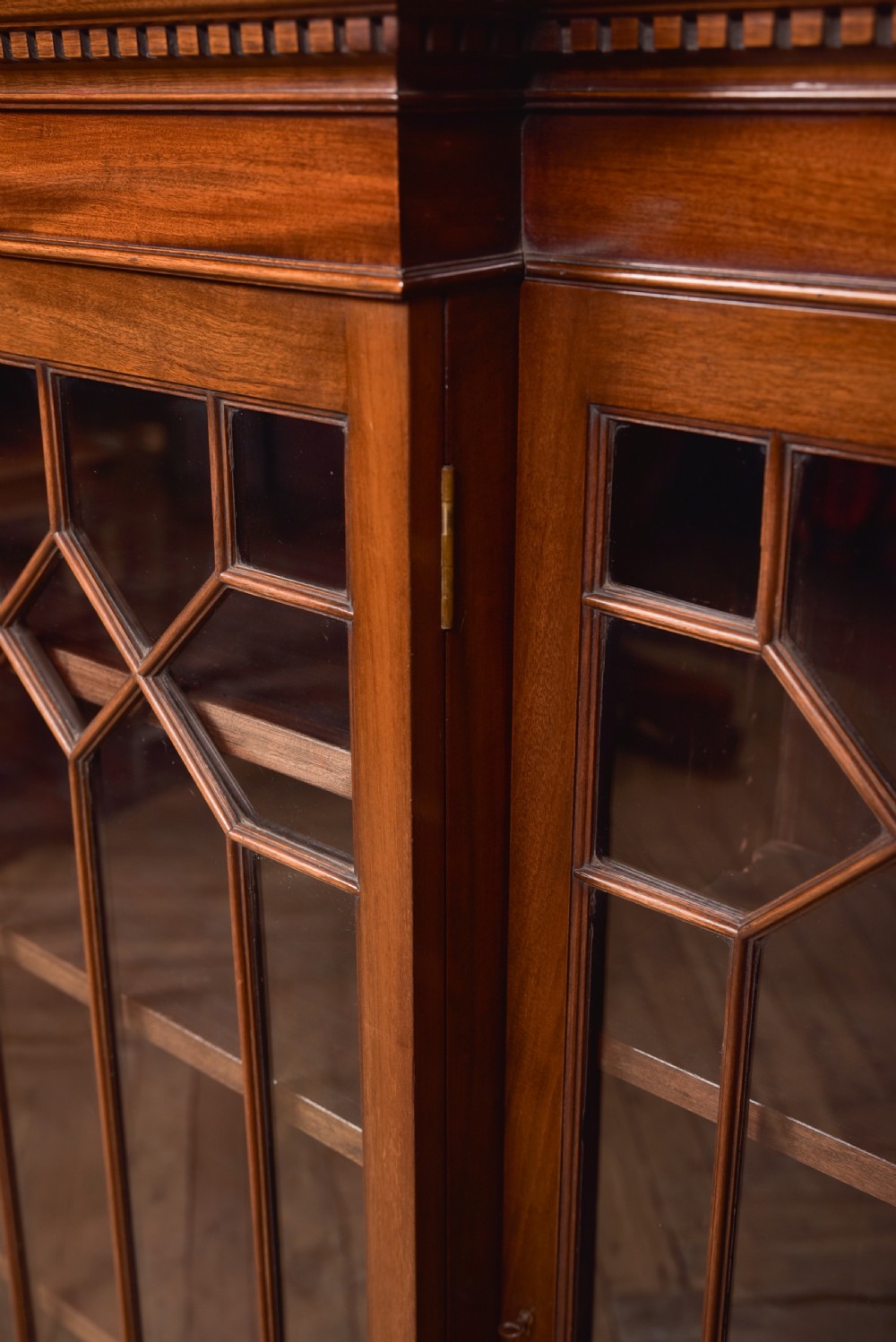A large mahogany Chinese Chippendale style breakout bookcase featuring four glazed doors with lattice astragal glazing and dentil moulding along the top. View XIV
