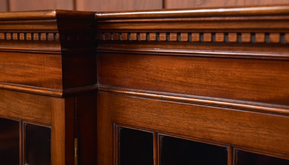 A large mahogany Chinese Chippendale style breakout bookcase featuring four glazed doors with lattice astragal glazing and dentil moulding along the top. View XV