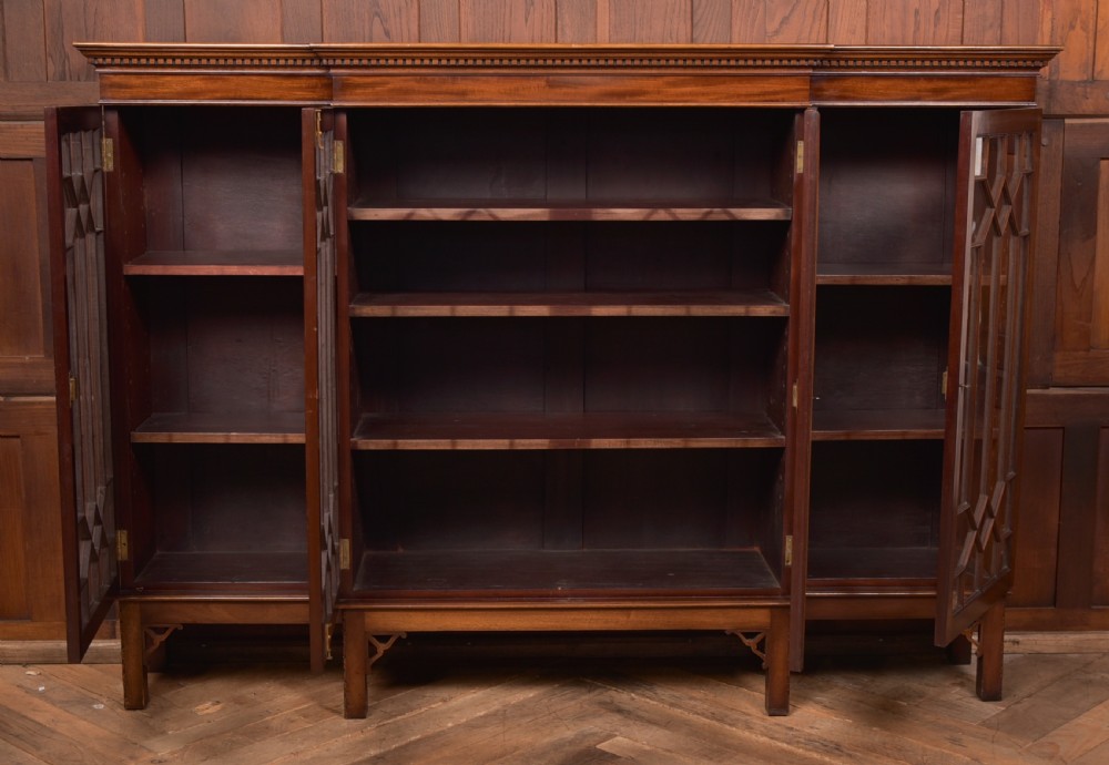 A large mahogany Chinese Chippendale style breakout bookcase featuring four glazed doors with lattice astragal glazing and dentil moulding along the top. View XVI