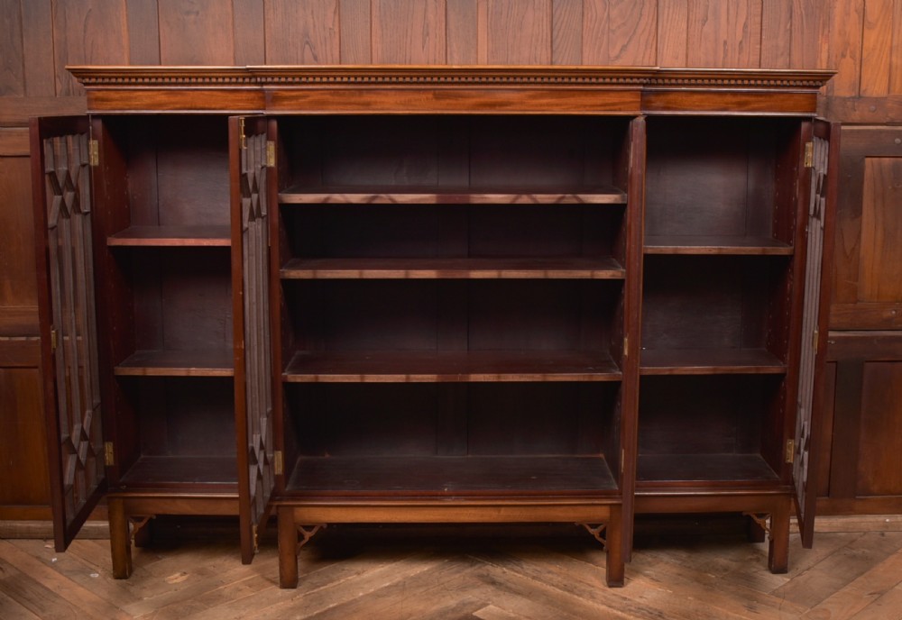 A large mahogany Chinese Chippendale style breakout bookcase featuring four glazed doors with lattice astragal glazing and dentil moulding along the top. View XVII